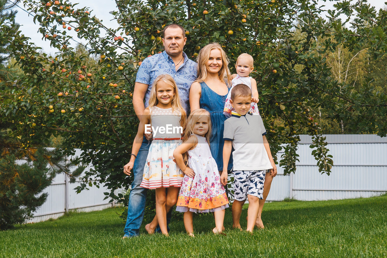 Portrait of family standing on grass against trees
