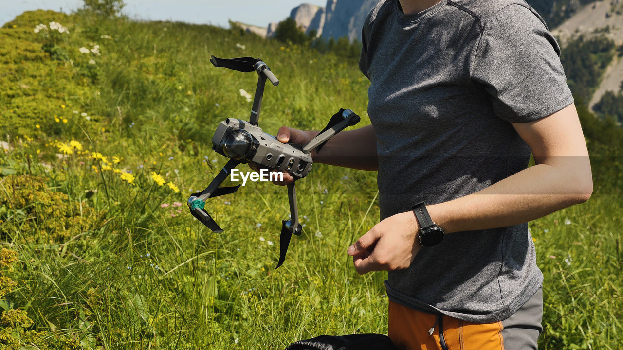 A man holds a quadcopter and prepares it for flight. launching a drone on a mountain hike