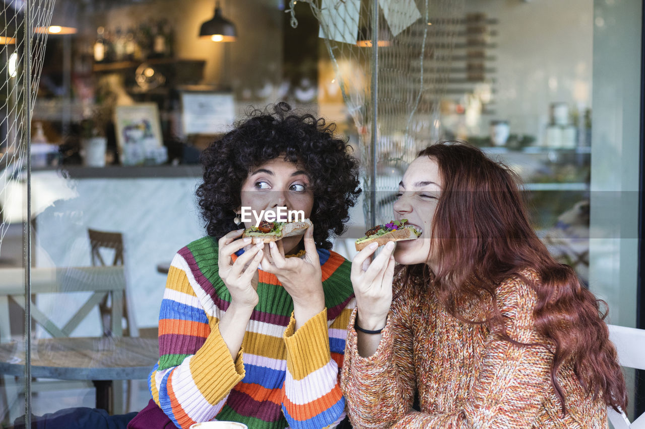 Young woman having breakfast with friend while sitting at restaurant