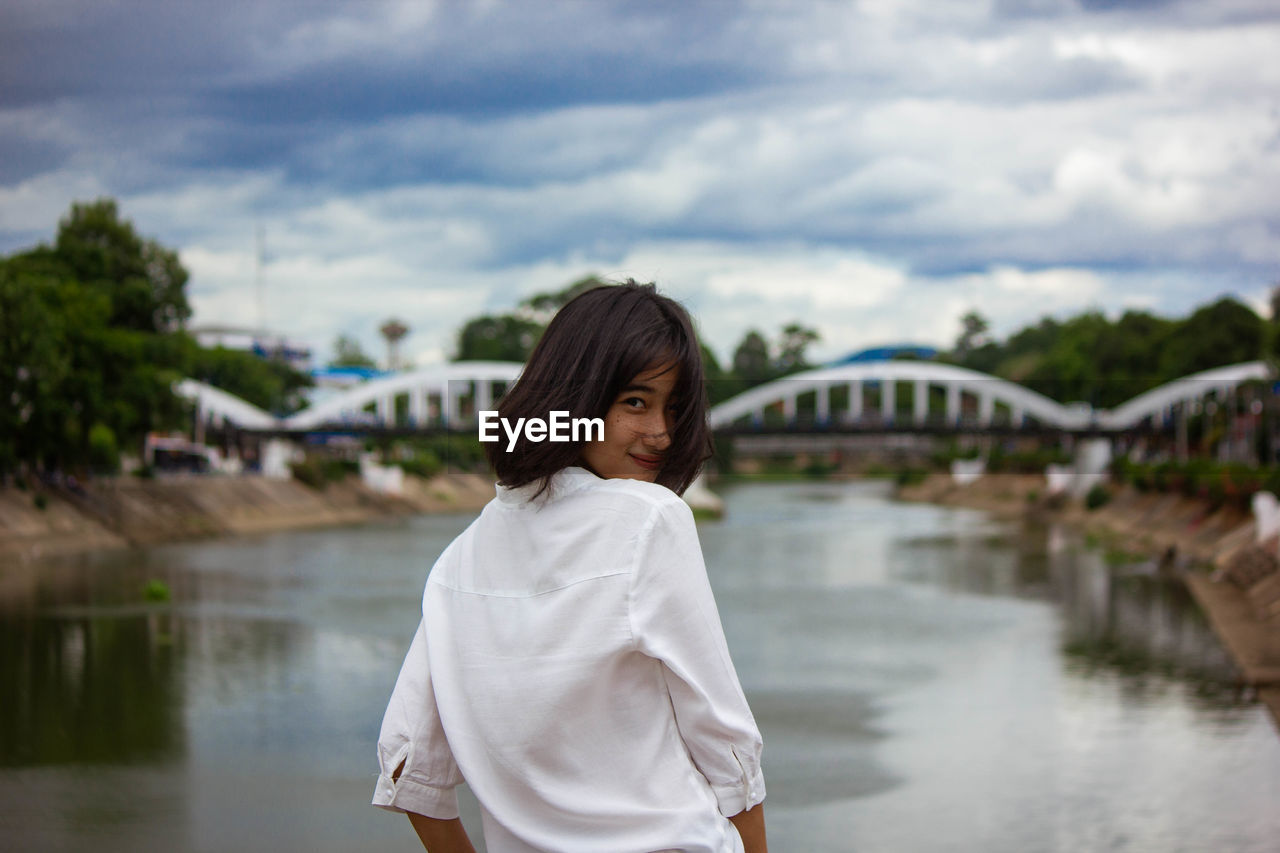 Girl standing on bridge over river against sky