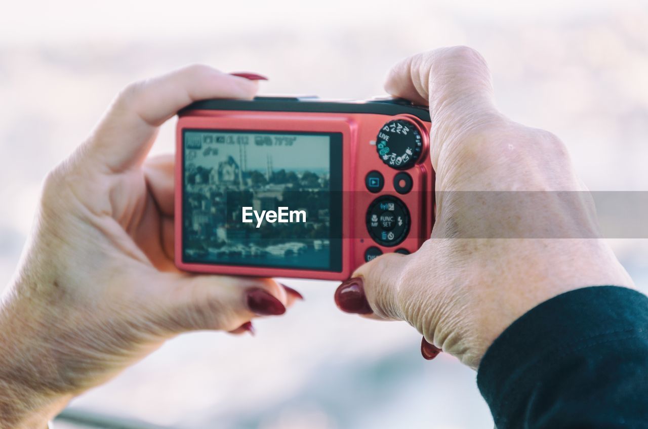 Cropped hand of woman photographing cityscape