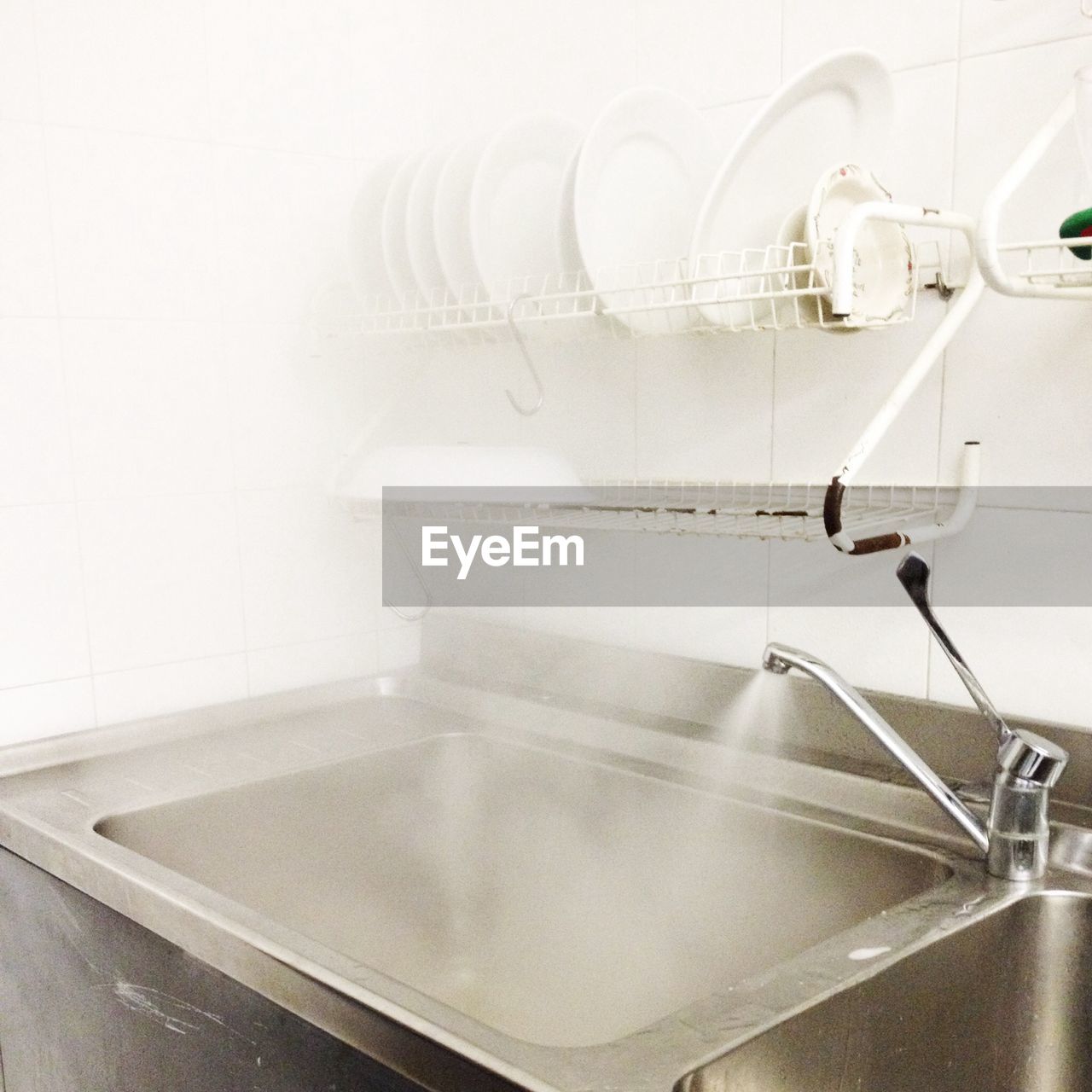 Close-up of washbasin with plates in rack in kitchen