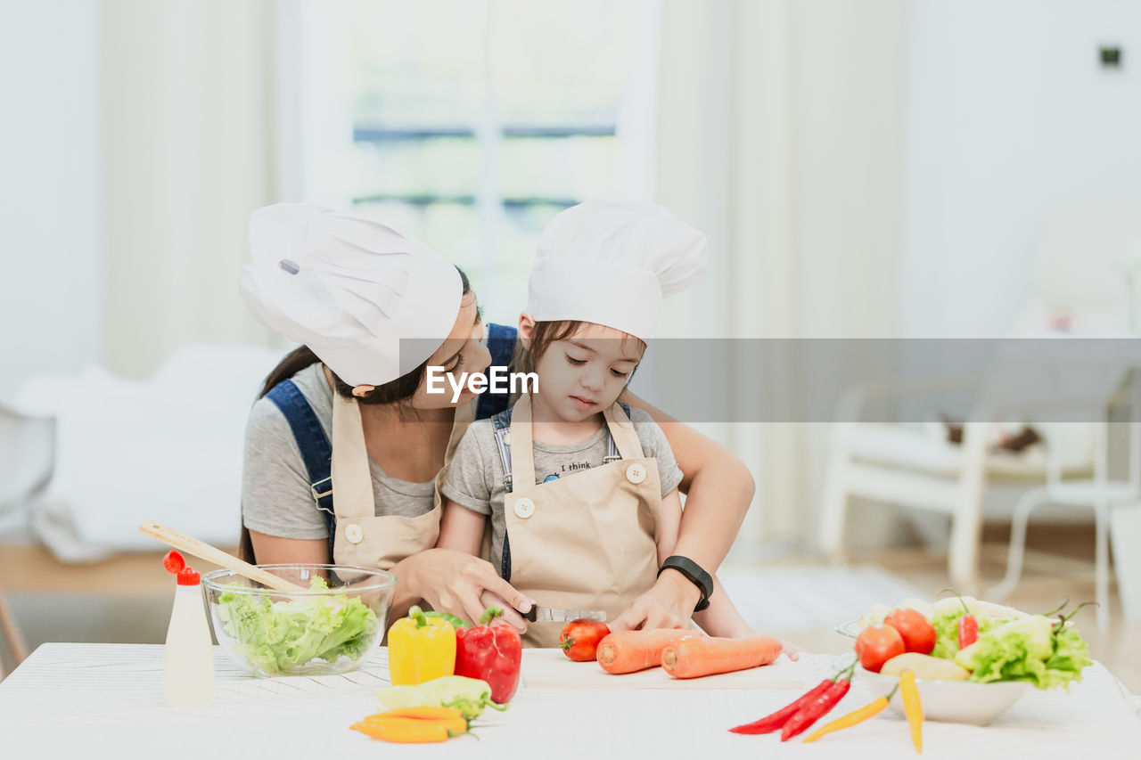 MIDSECTION OF WOMAN PREPARING FOOD AT KITCHEN