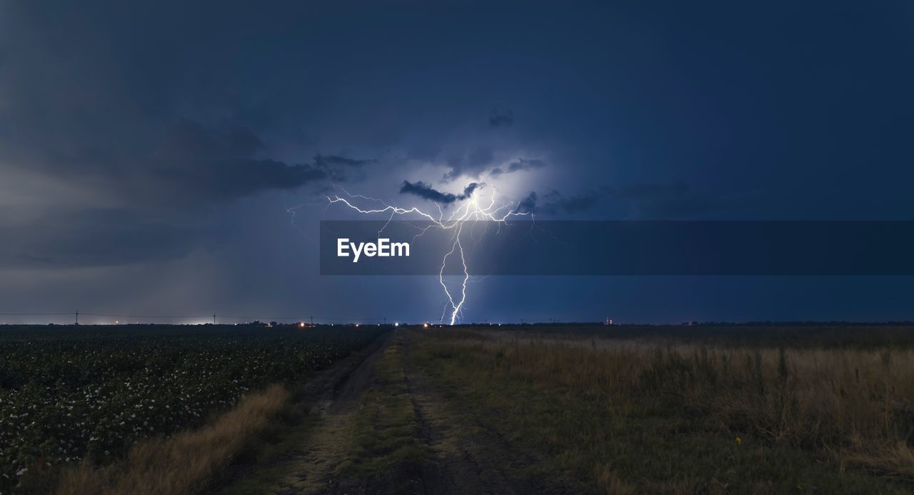 LIGHTNING OVER FIELD AGAINST STORM CLOUDS