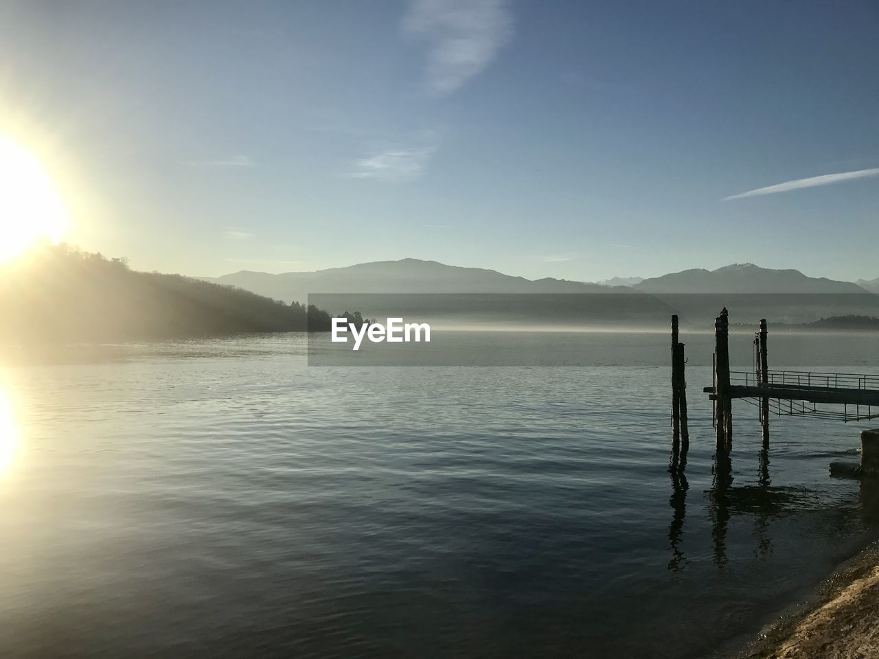 water, sky, horizon, reflection, sea, beauty in nature, morning, scenics - nature, nature, tranquility, mountain, dawn, tranquil scene, sunrise, body of water, shore, sunlight, ocean, cloud, sun, coast, land, outdoors, beach, idyllic, environment, sunbeam, bay, day, pier, mountain range, silhouette, non-urban scene, wave, no people, landscape, travel destinations, travel, lens flare, vacation, trip, holiday, transportation