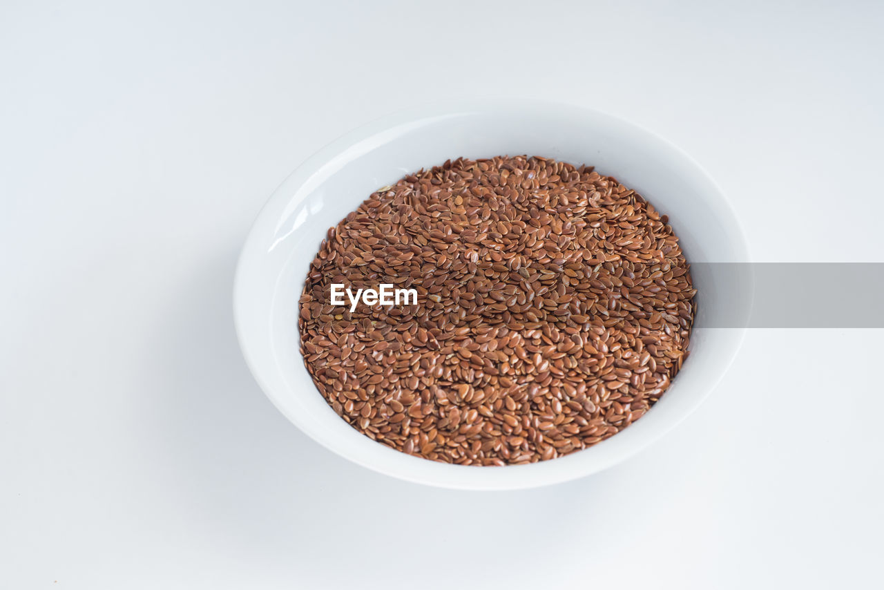 Flax seeds in bowl over white background