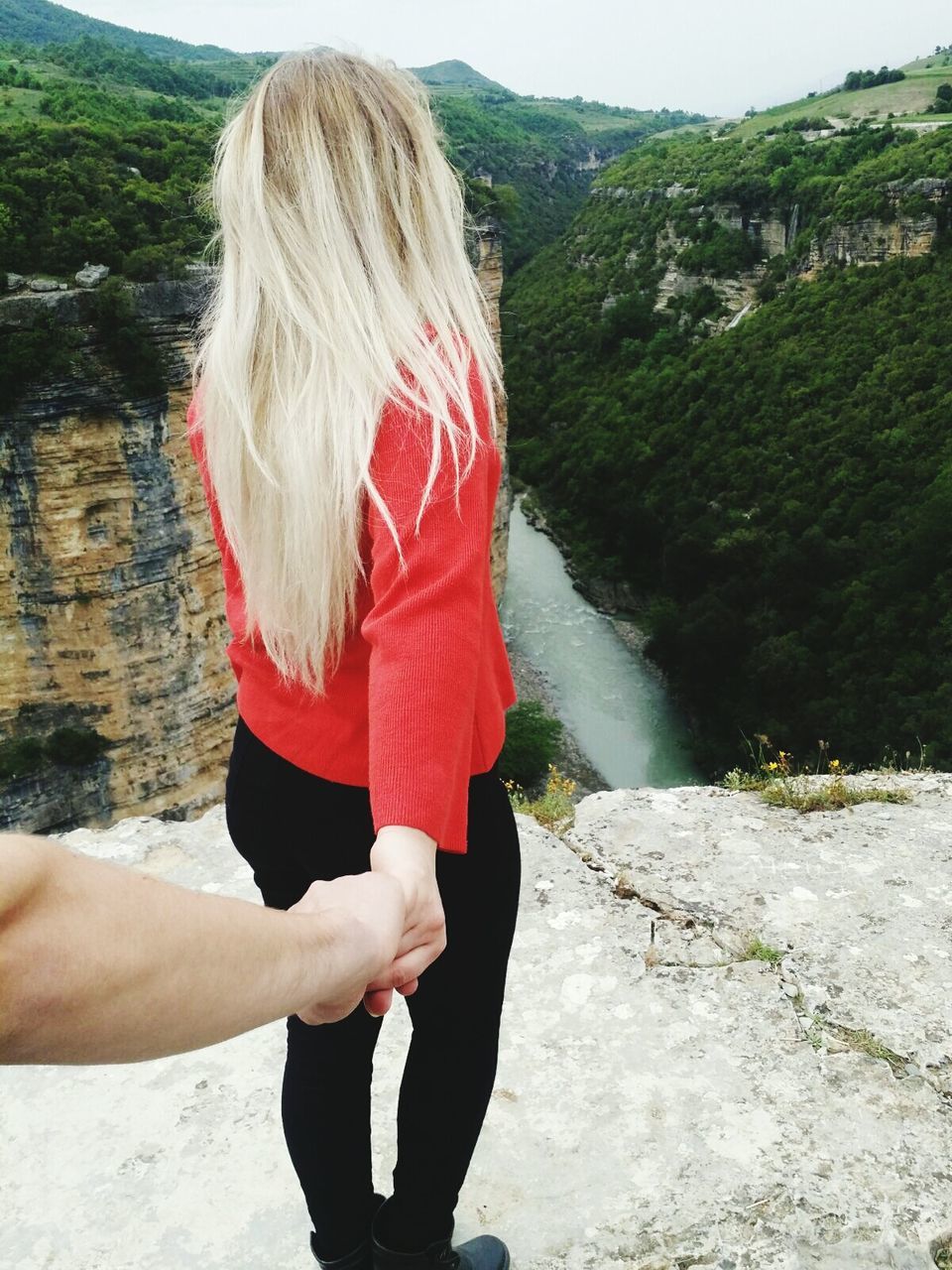 Cropped image of man holding woman hand on mountain