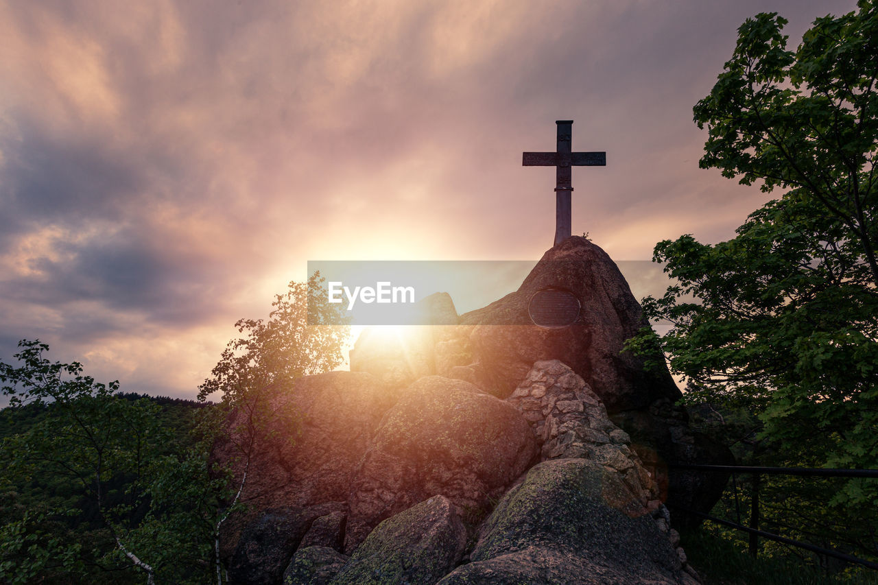 LOW ANGLE VIEW OF CROSS ON ROCK AGAINST SKY
