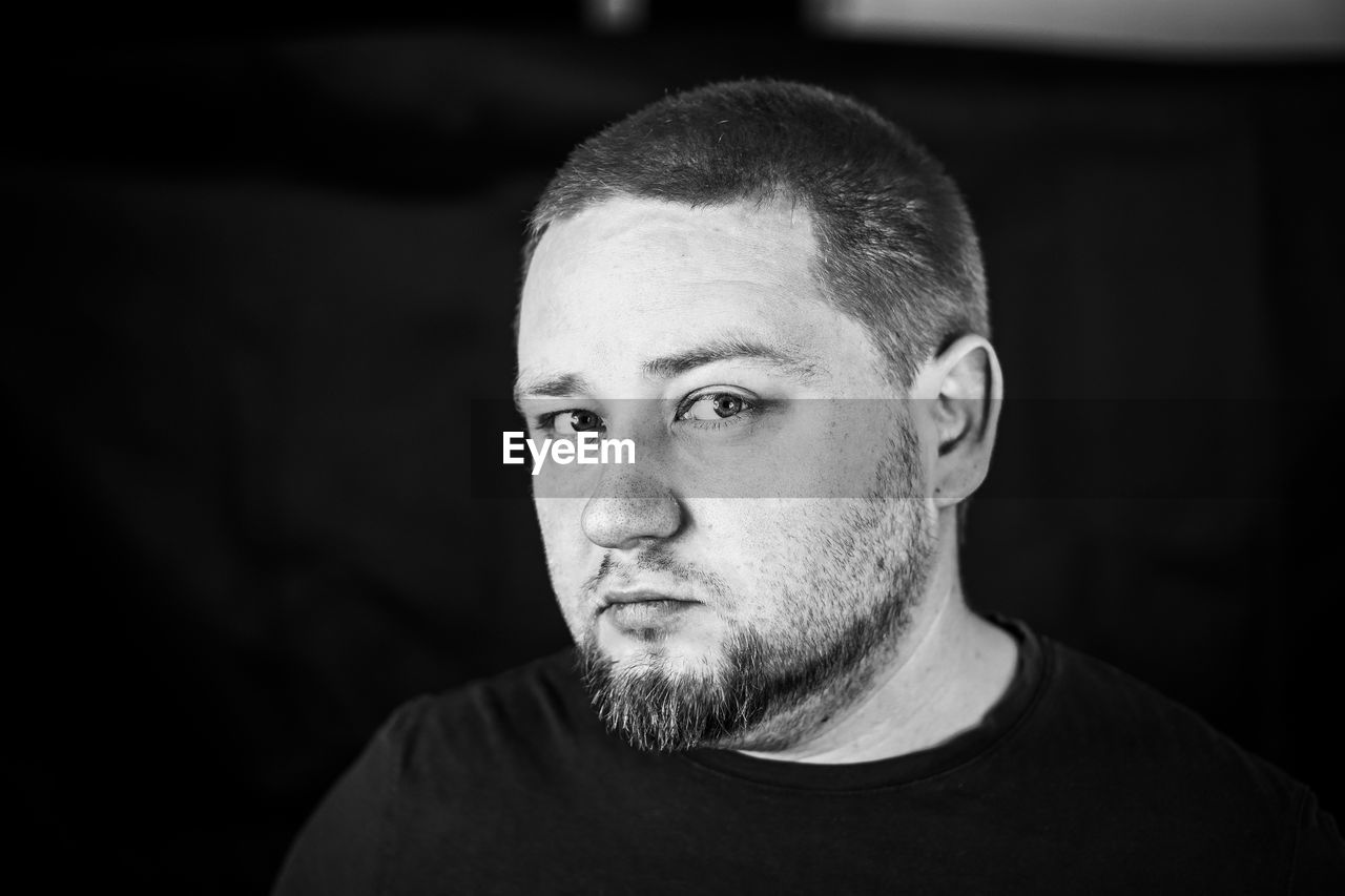 Close-up portrait of serious man against black backdrop