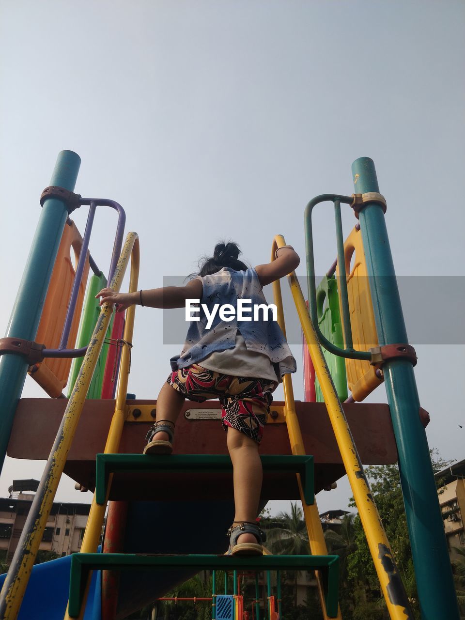 Rear view of girl climbing outdoors play equipment