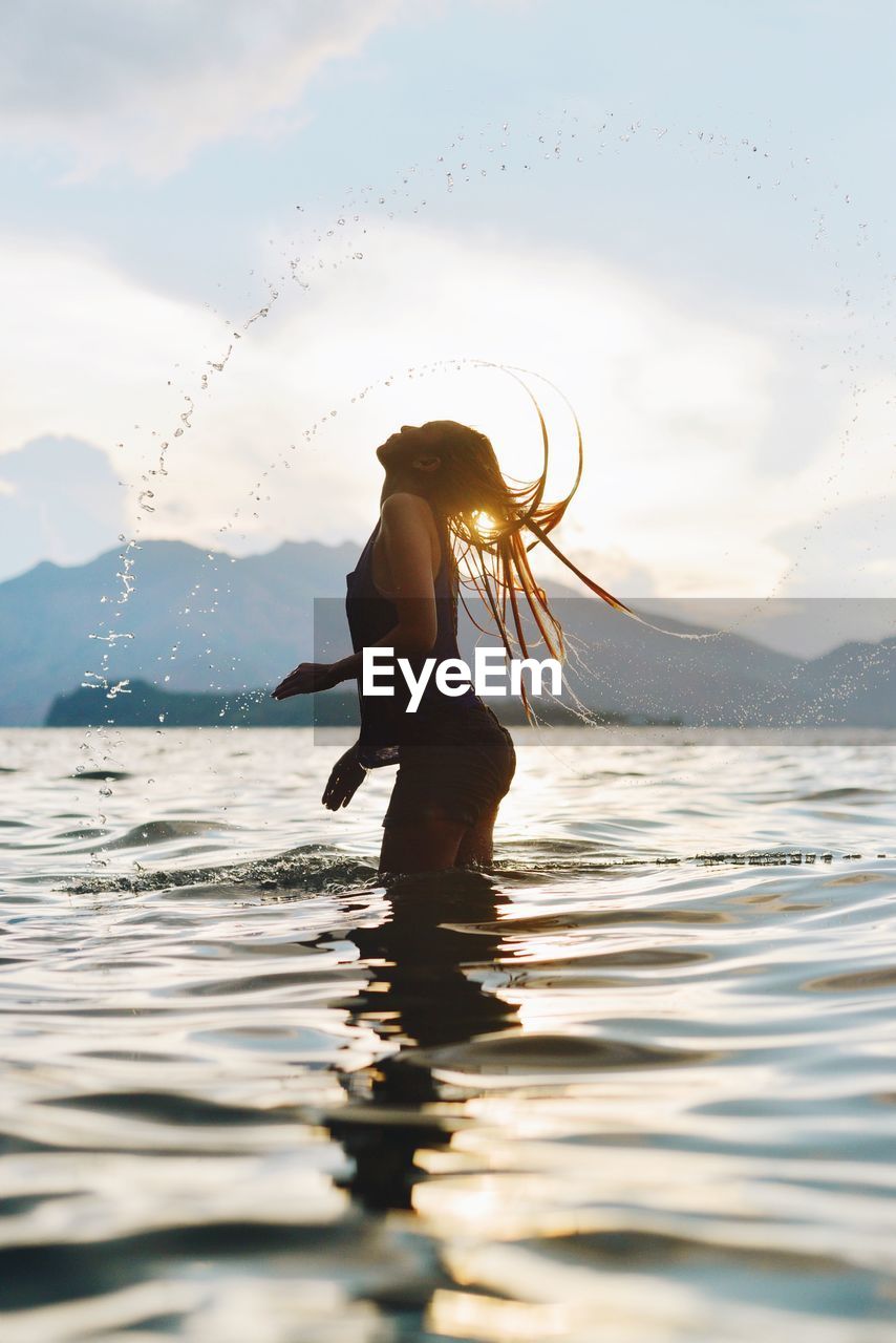 Wet beautiful woman against sky in sea