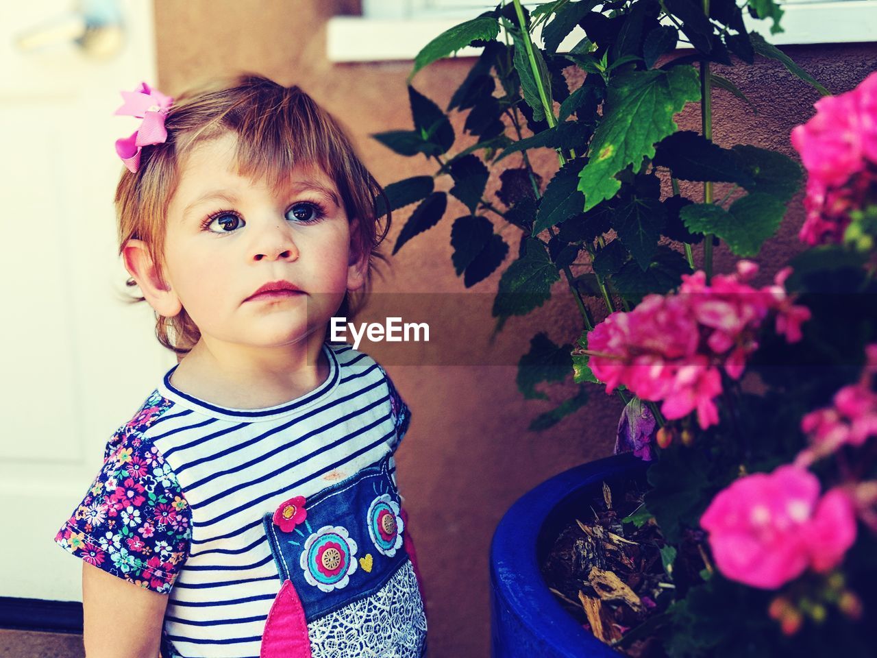 Cute girl looking away by flowering plants outdoors