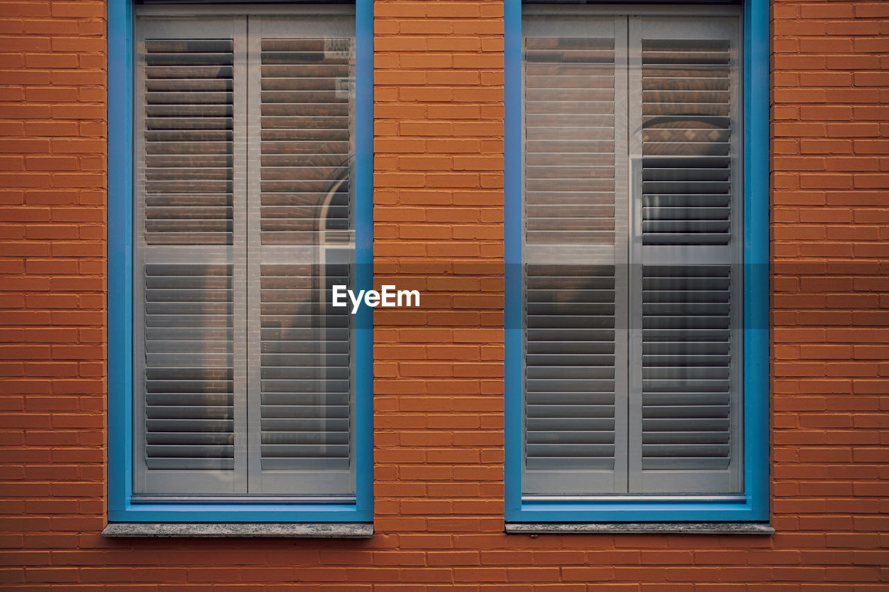 Blue framed window with blinds in red brick wall