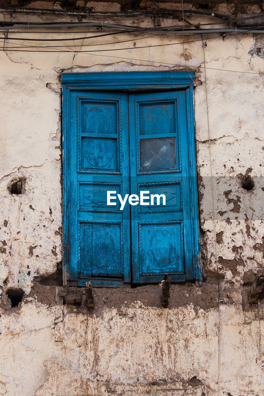 Low angle view of blue window in abandoned building