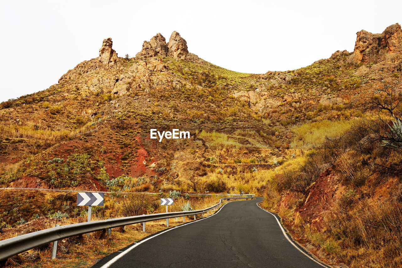 Empty road amidst mountains against clear sky at pilancones park