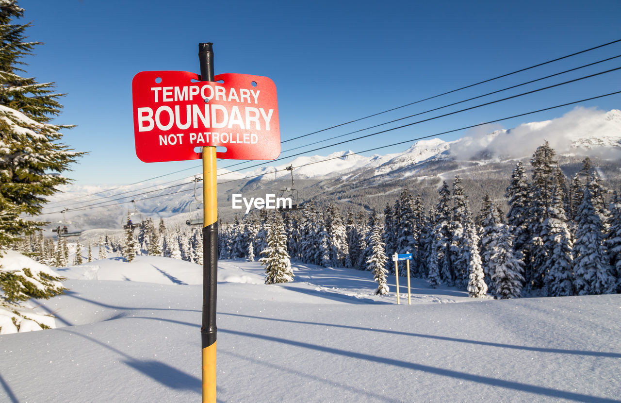 WARNING SIGN ON SNOW COVERED MOUNTAIN AGAINST SKY