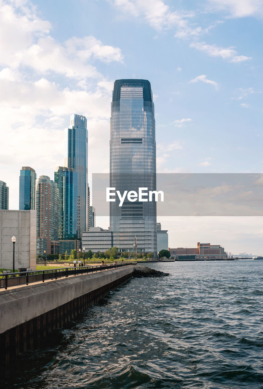 Sea by modern buildings against sky in city