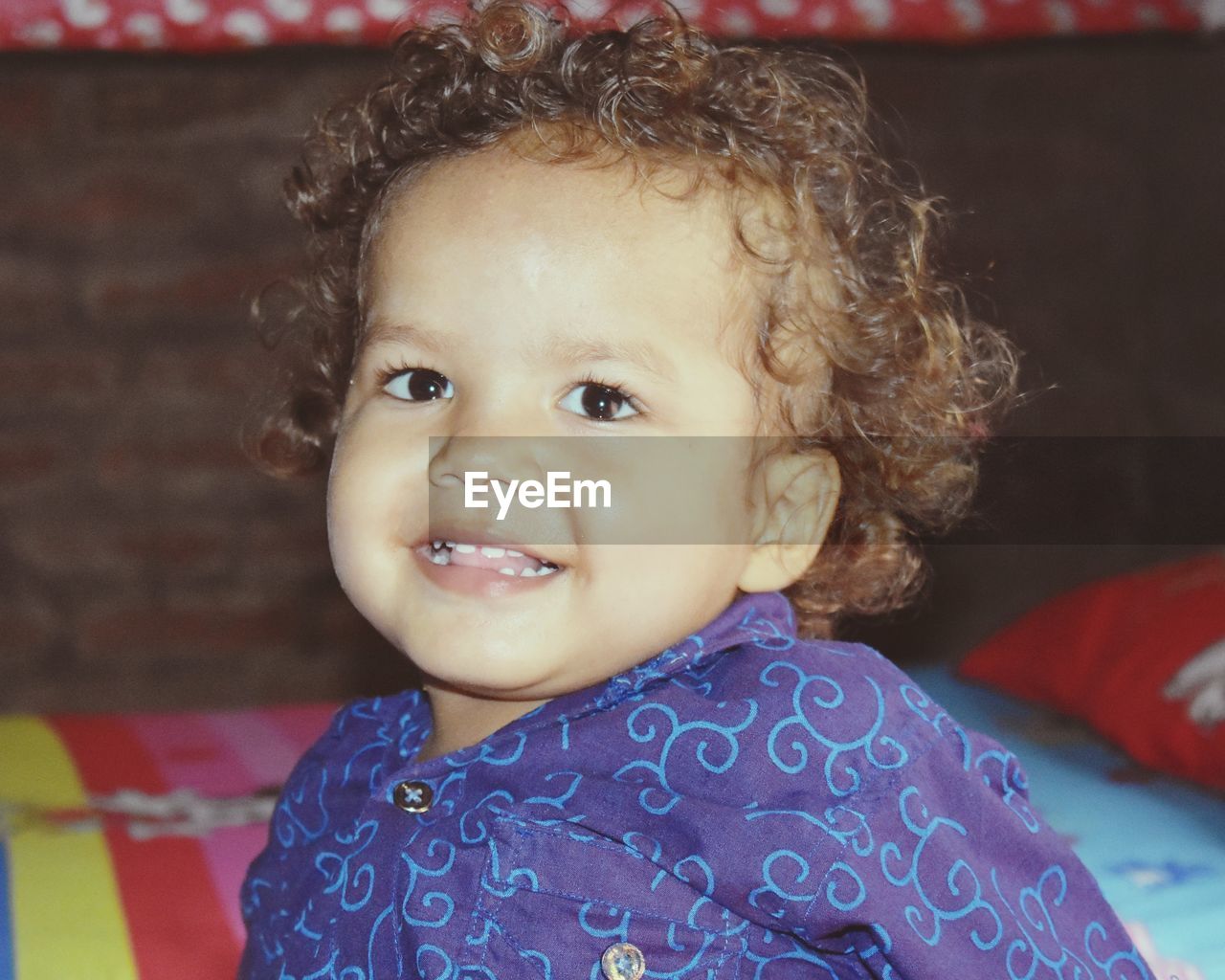 child, childhood, portrait, one person, baby, innocence, cute, smiling, looking at camera, curly hair, person, happiness, emotion, headshot, indoors, babyhood, toddler, front view, cheerful, clothing, close-up, focus on foreground, baby clothing, human face, lifestyles, female, eye, skin, looking, brown eyes, home interior, hairstyle, sitting, casual clothing, pattern, women