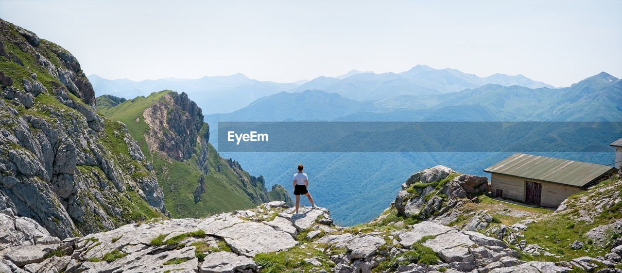 A woman looks at the landscape from the top of a mountain