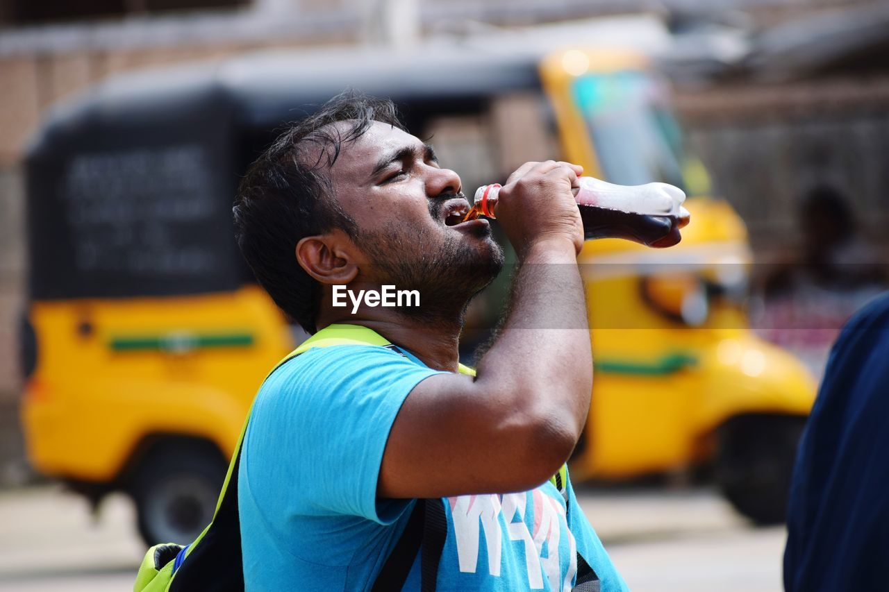 Man drinking drink from bottle in city