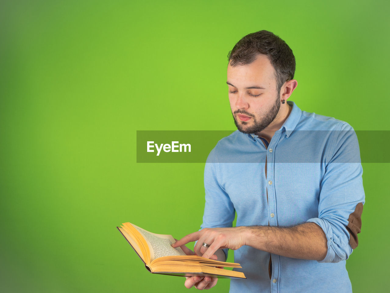 YOUNG MAN LOOKING AWAY WHILE HOLDING BOOK