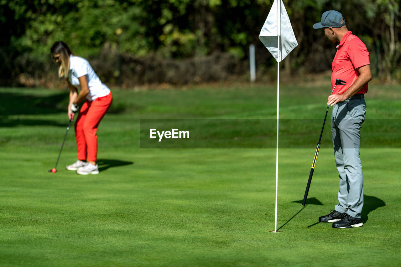 A woman and a man playing golf, woman putting