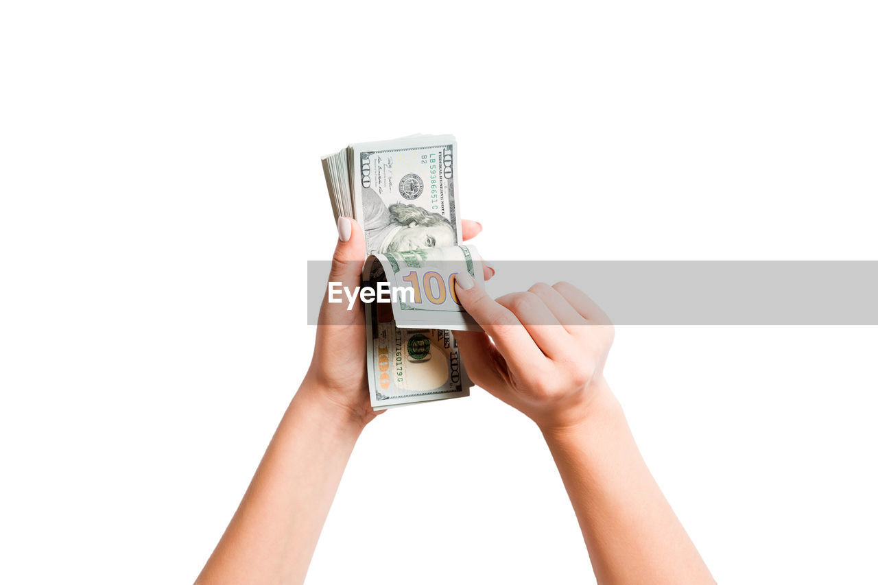 Cropped hands of woman holding paper currency against white background