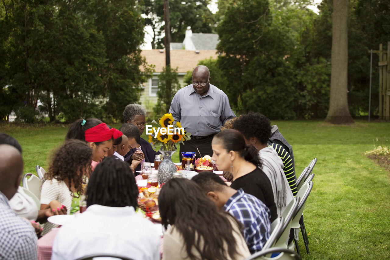 Family and friends having food at table in backyard