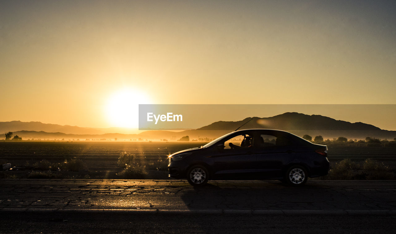 Car on road against sky during sunset