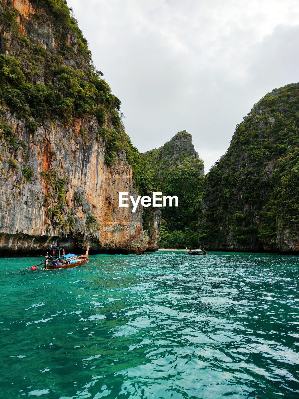 Scenic view of sea by mountain against cloudy sky