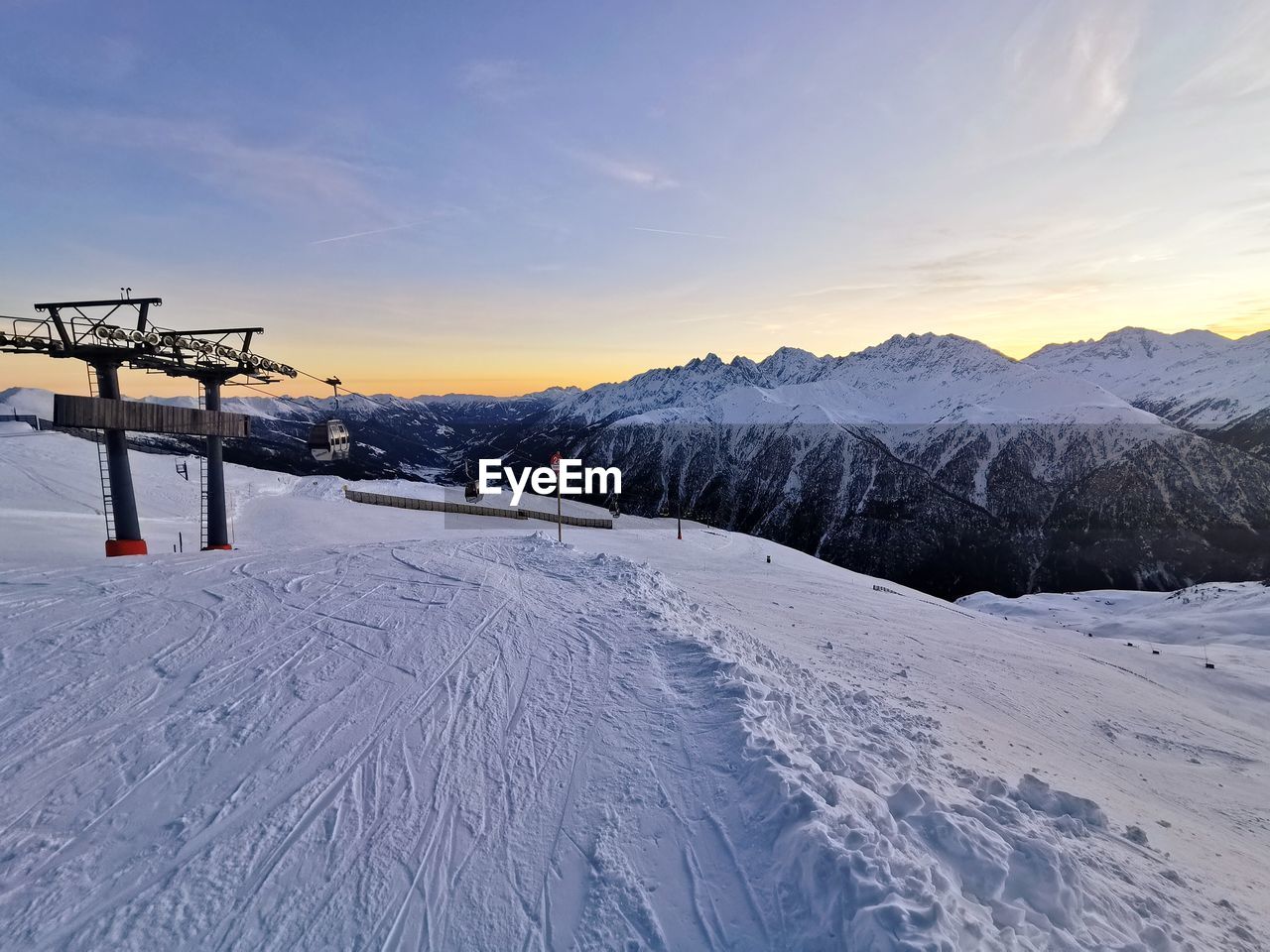 SCENIC VIEW OF SNOW COVERED MOUNTAINS AGAINST SKY DURING SUNSET