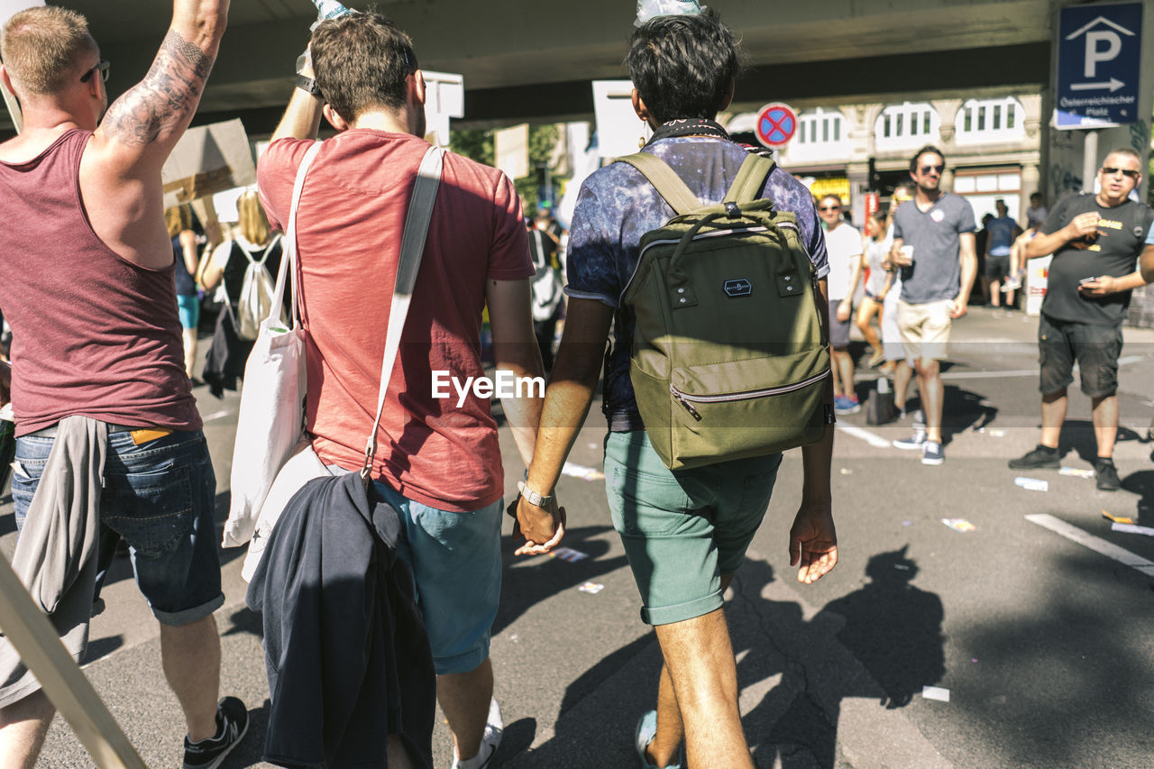 REAR VIEW OF TWO PEOPLE STANDING ON STREET