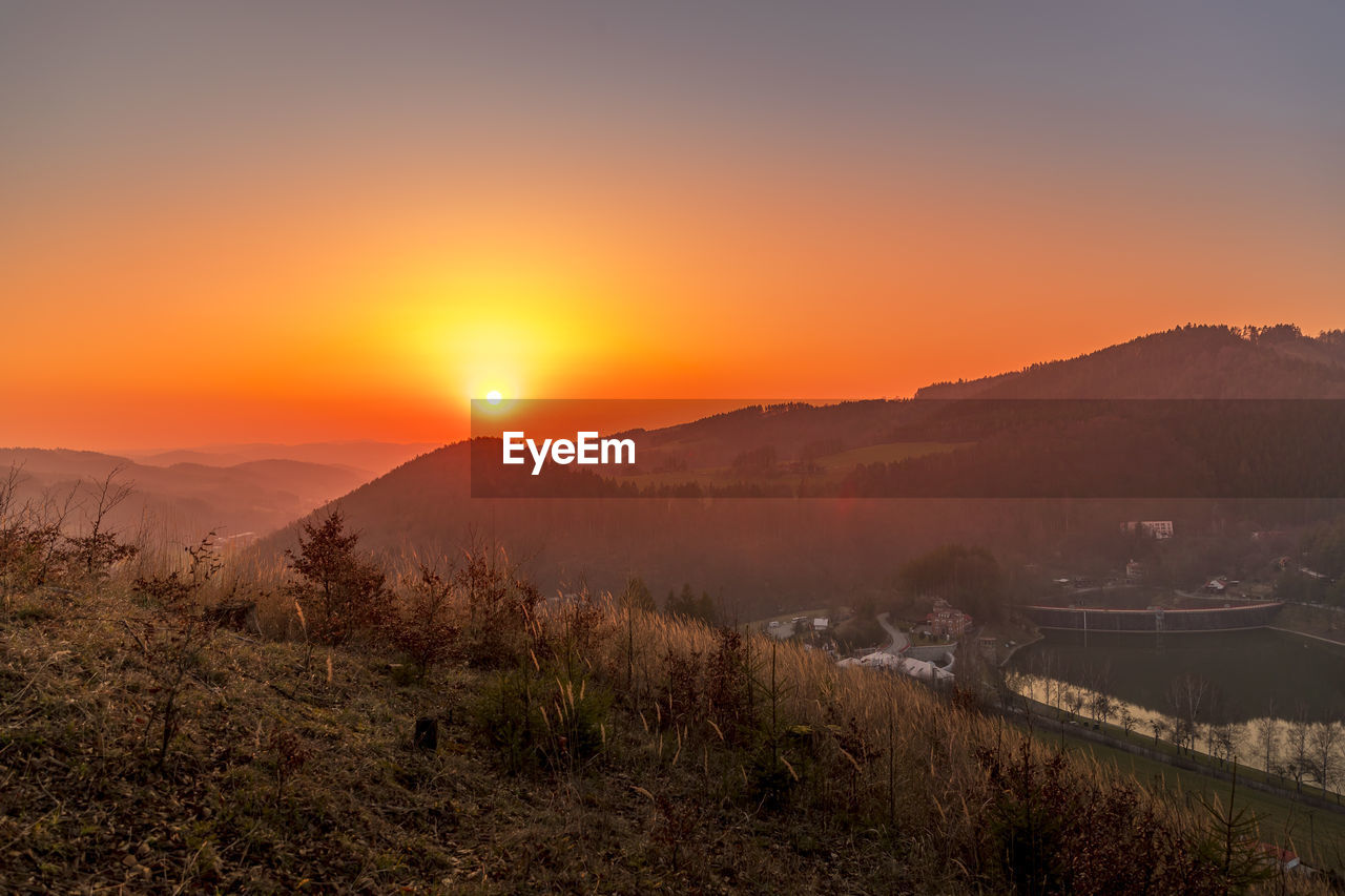 SCENIC VIEW OF MOUNTAINS AGAINST ORANGE SKY