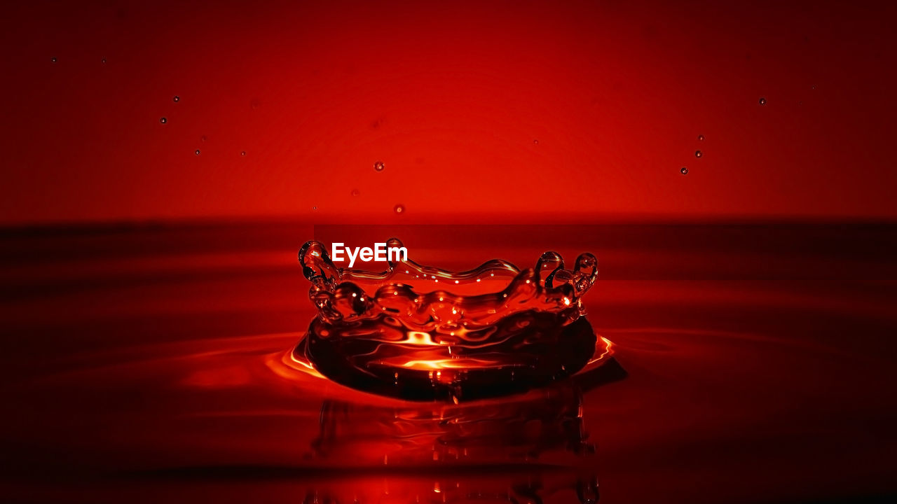 CLOSE-UP OF WATER DROP ON RED BACKGROUND