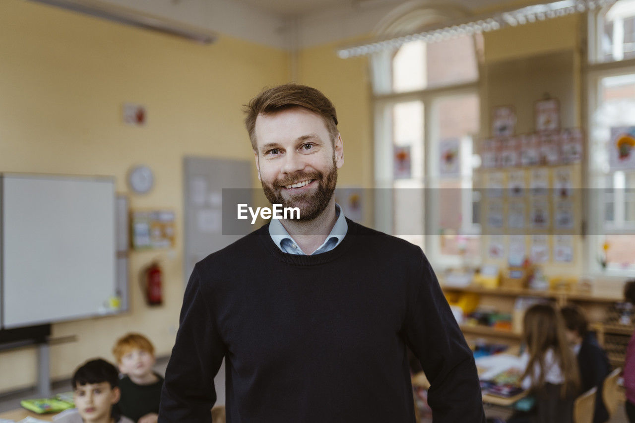 Portrait of smiling mature male teacher in classroom