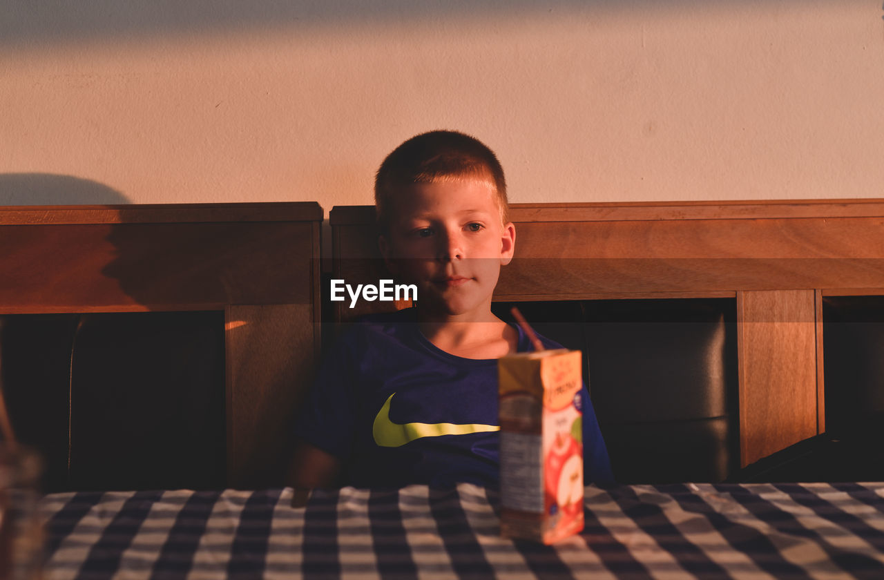 PORTRAIT OF BOY SITTING ON FLOOR AT HOME