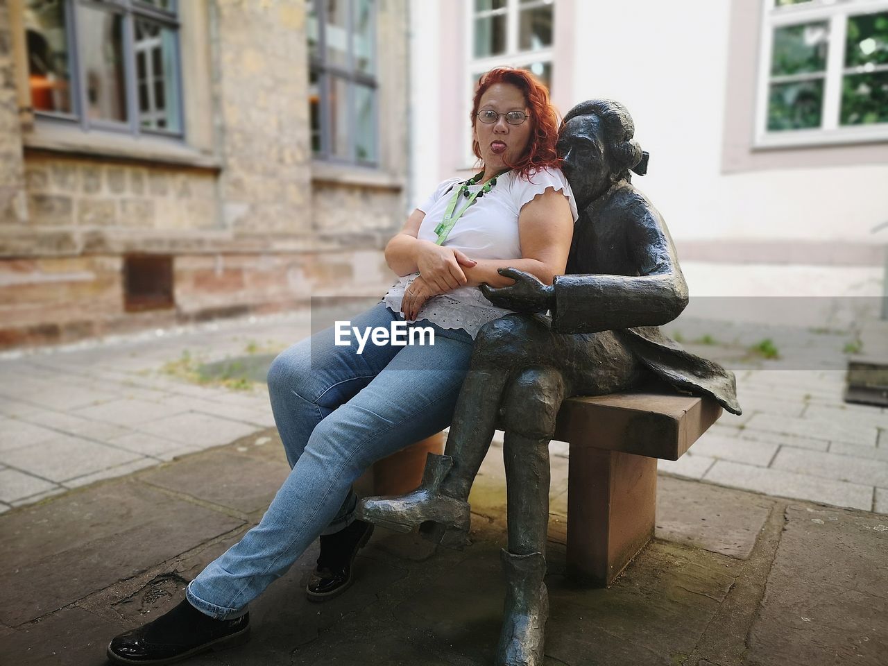 Full length of woman sitting outside building against statue 