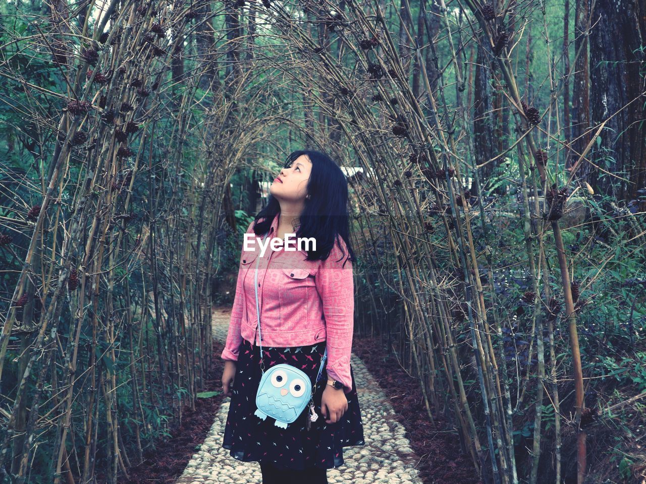 WOMAN STANDING BY TREE TRUNK