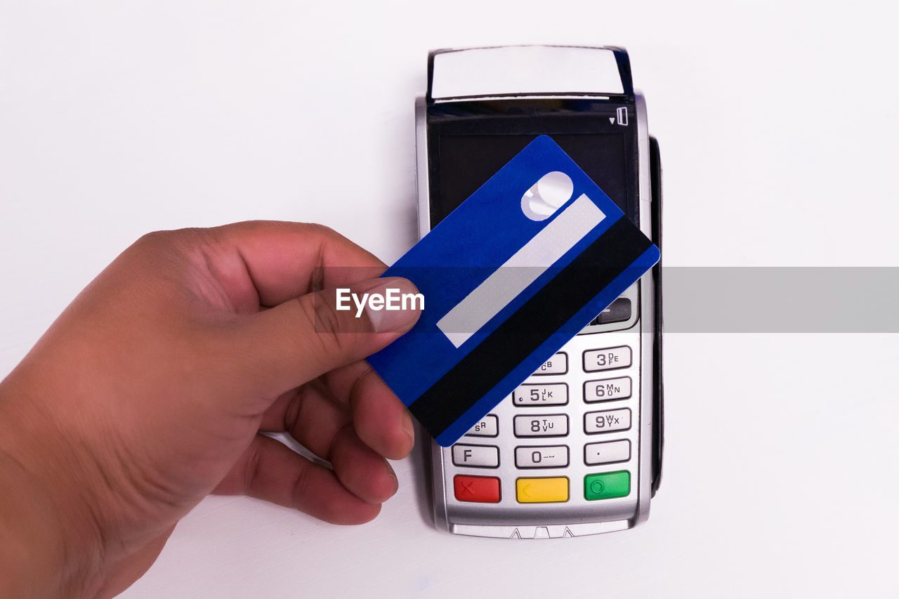 CLOSE-UP OF PERSON HOLDING MOBILE OVER WHITE BACKGROUND