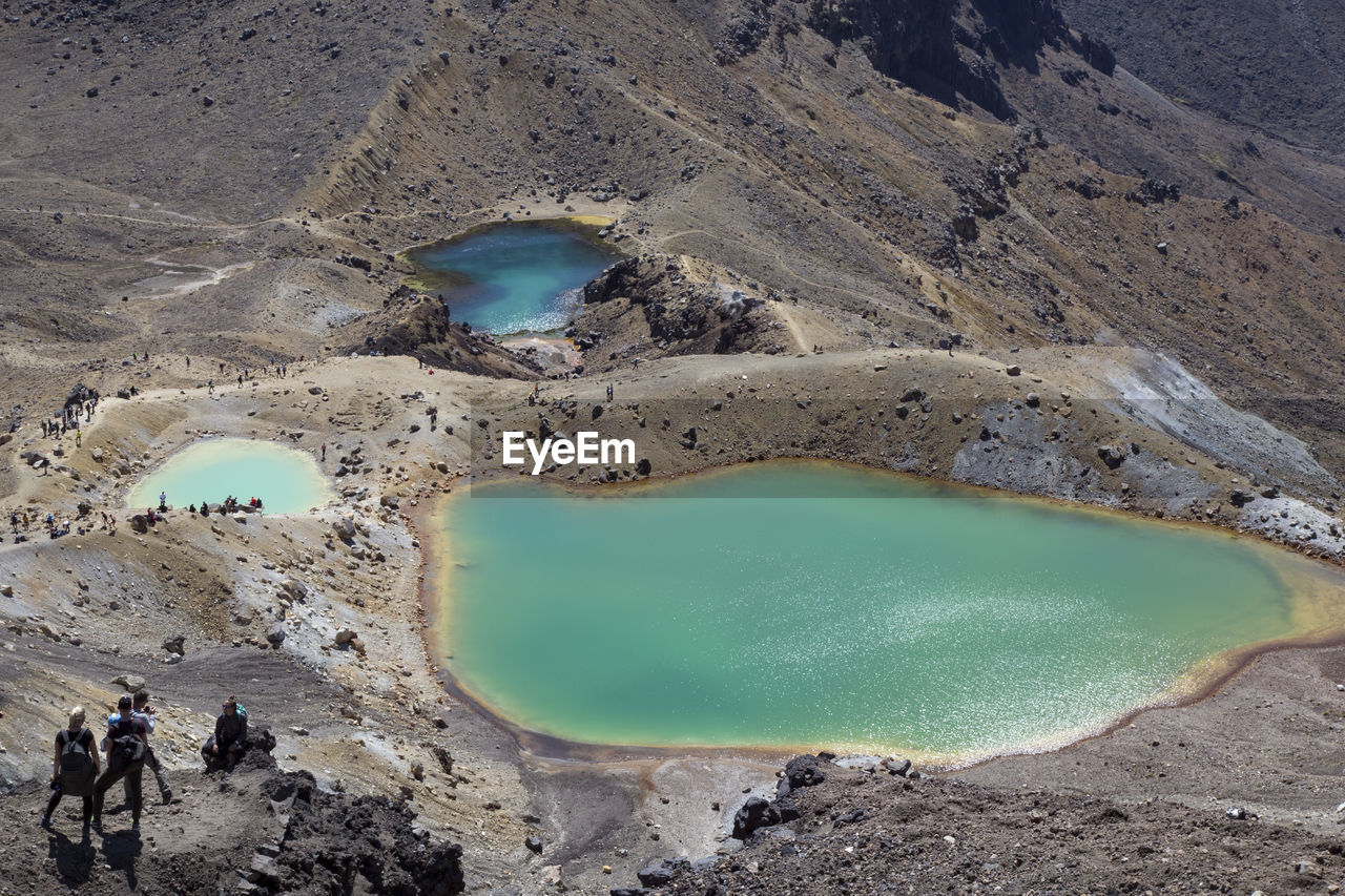 People hiking next to iconic emerald lakes at tongariro crossing trail