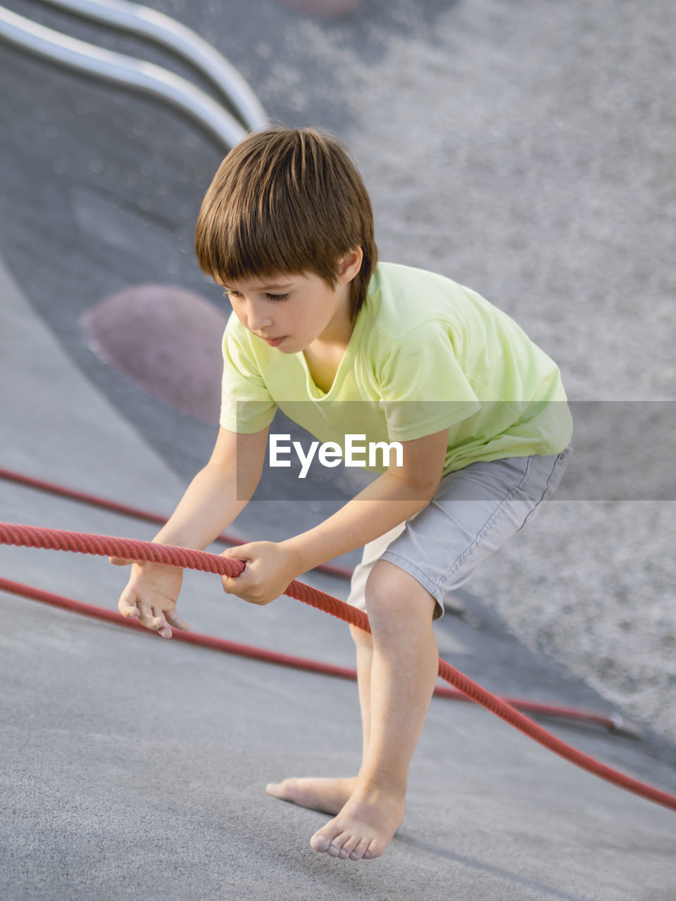 Boy climbes up a concrete slope of modern  sportsground. kid overcomes fear and learn new things. 