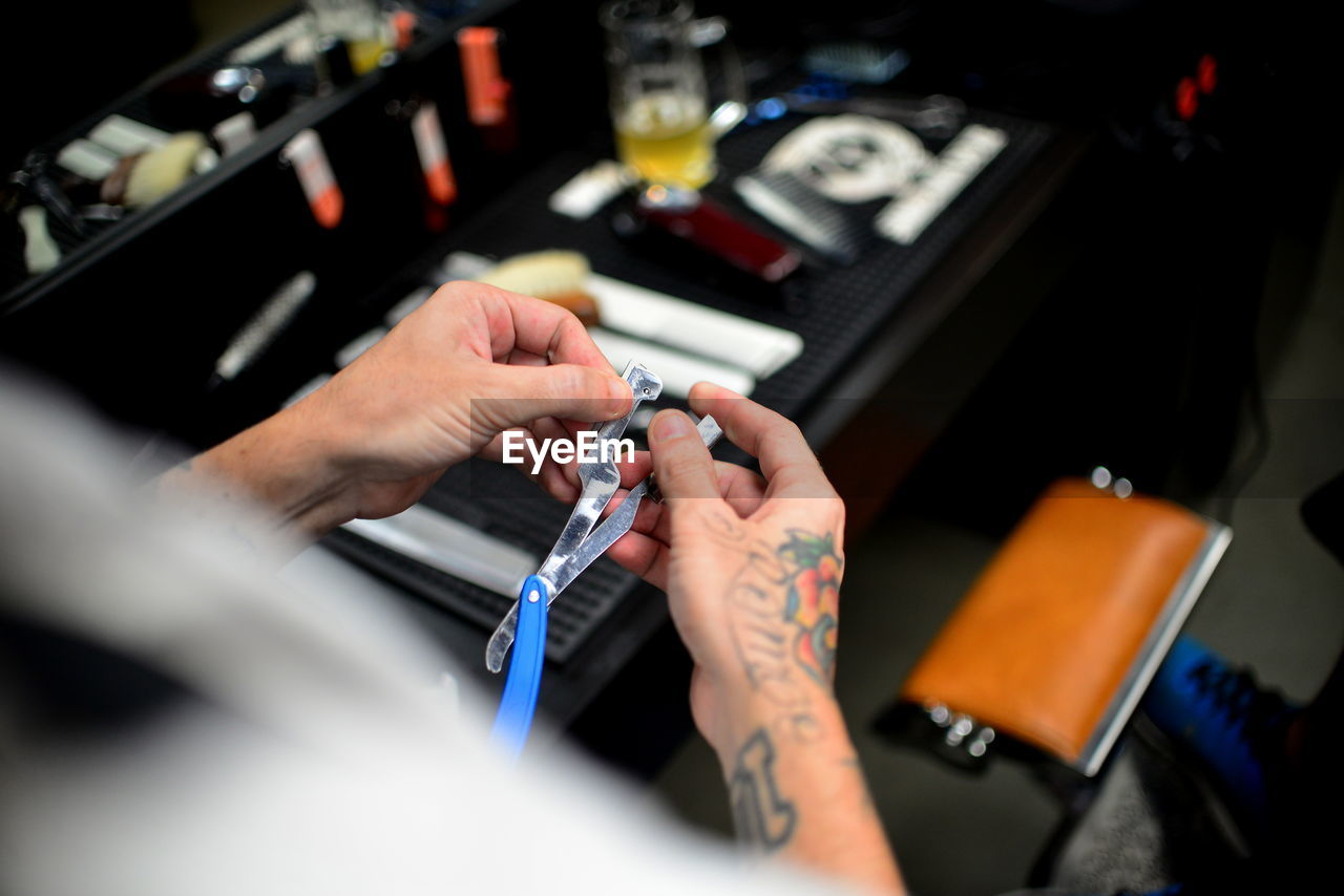 Close-up of tattooed hand of a barber holding straight razor