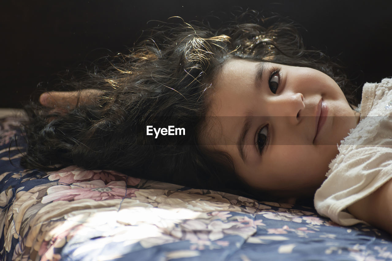 Portrait of cute girl lying on bed at home