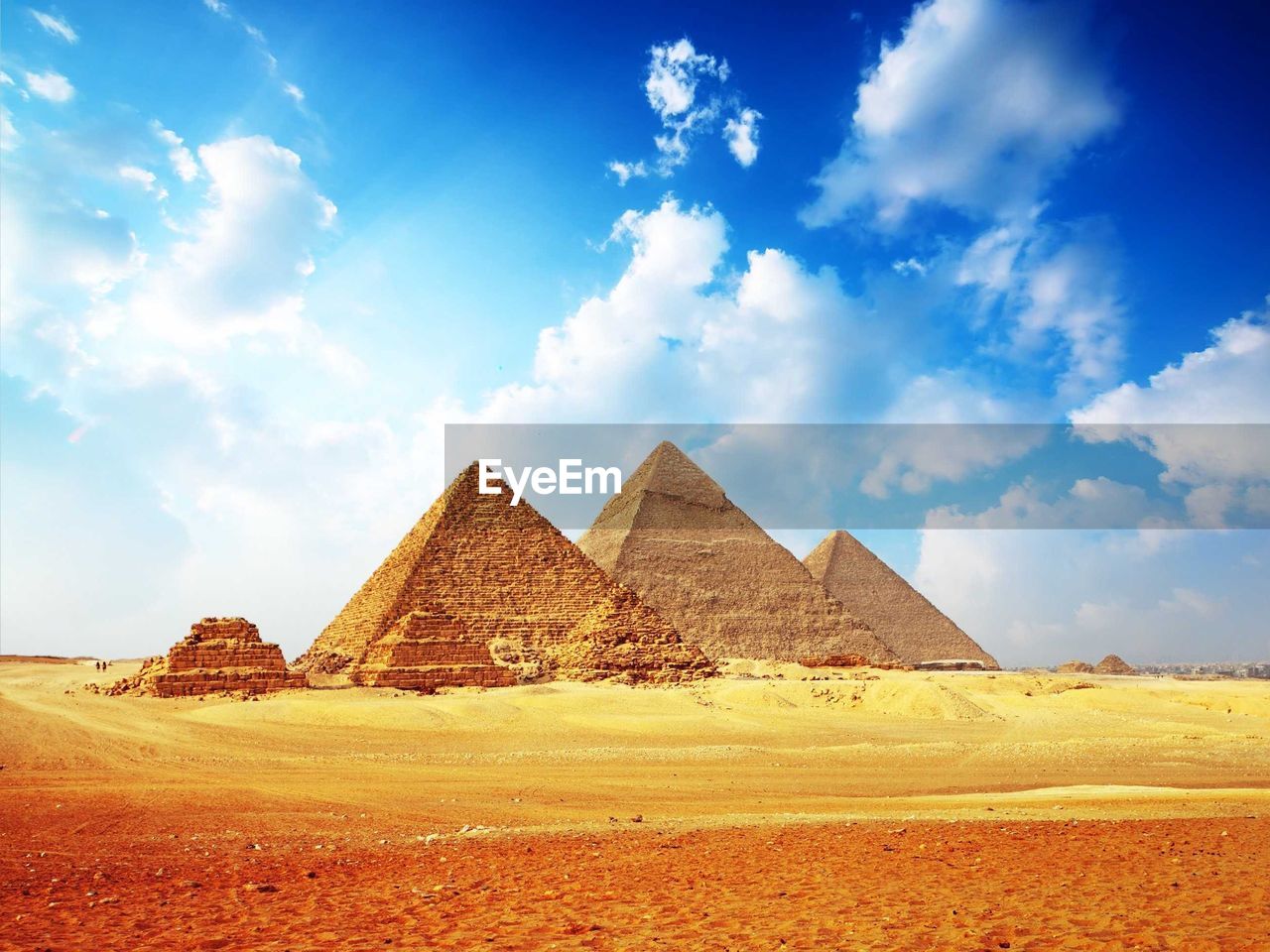 Pyramids in desert against cloudy sky