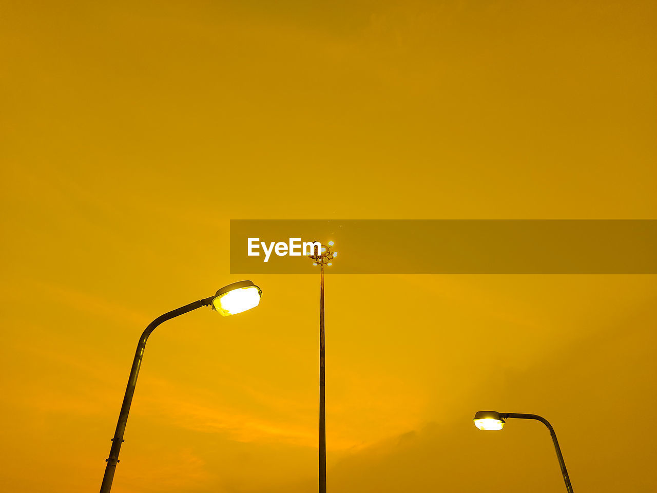 Low angle view of illuminated street light against orange sky