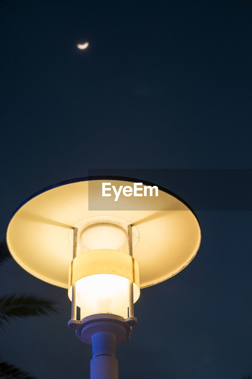 High section of lit lamp against clear sky