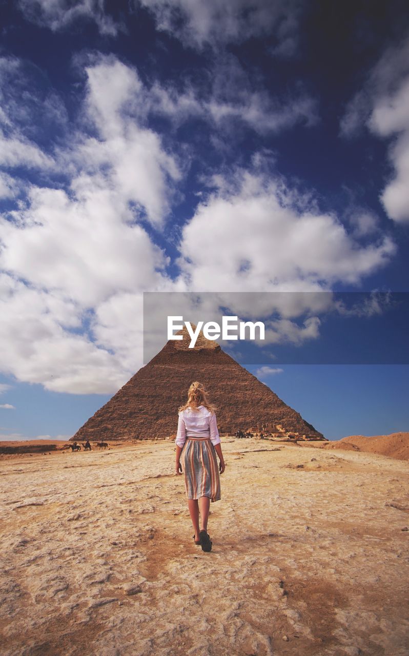 Woman walking on landscape against sky