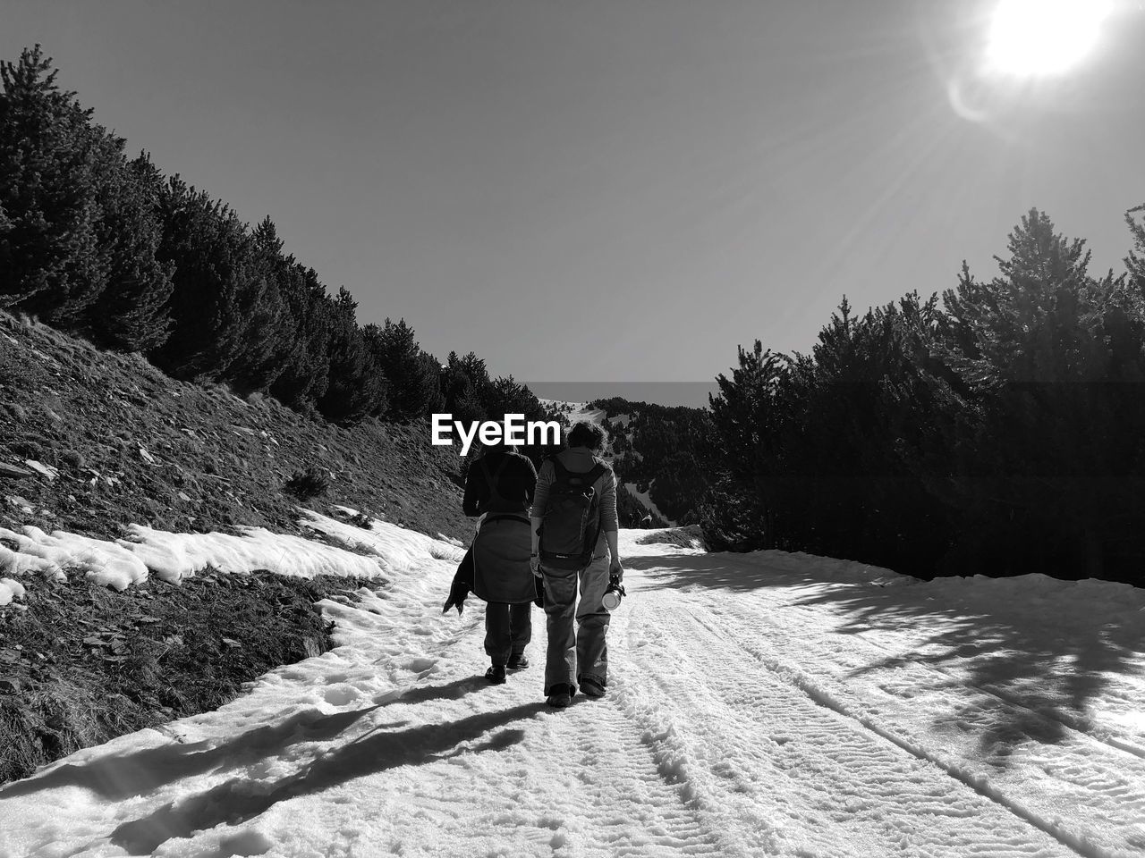 REAR VIEW OF COUPLE WALKING ON SNOW COVERED FIELD