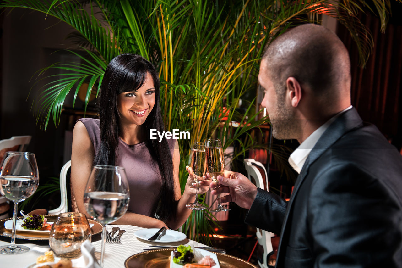 HAPPY FRIENDS SITTING AT RESTAURANT TABLE