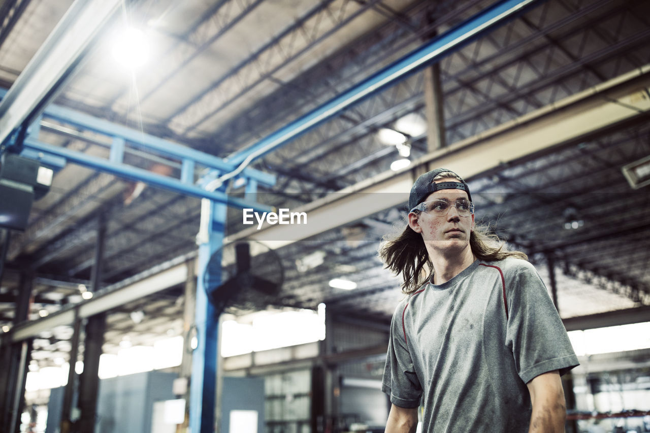 Worker looking away while standing in steel factory